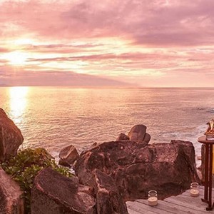 Constance Lemuria - Luxury Seychelles Honeymoon Packages - couple watching the sunset with a glass of champagne